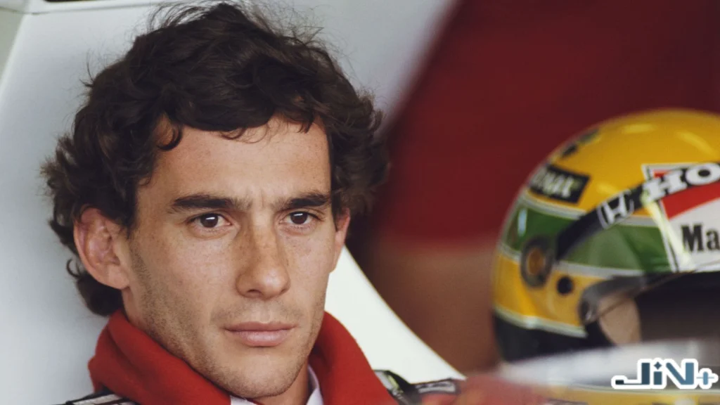 F1車神Ayrton Senna身穿麥拉倫紅色賽車服，在賽道維修區整備、身旁放置著經典黃綠巴西國旗配色賽車頭盔的特寫。