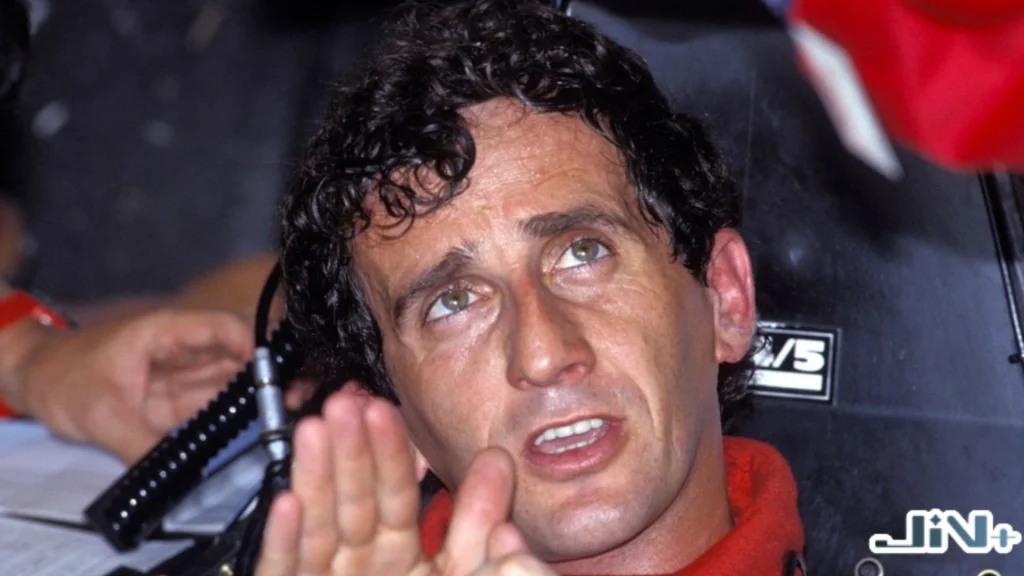 艾爾頓洗拿的一生宿敵、四屆世界冠軍「教授」保魯斯（Alain Prost）身穿紅色賽車服，在闈場內若有所思並舉手發言的特寫。