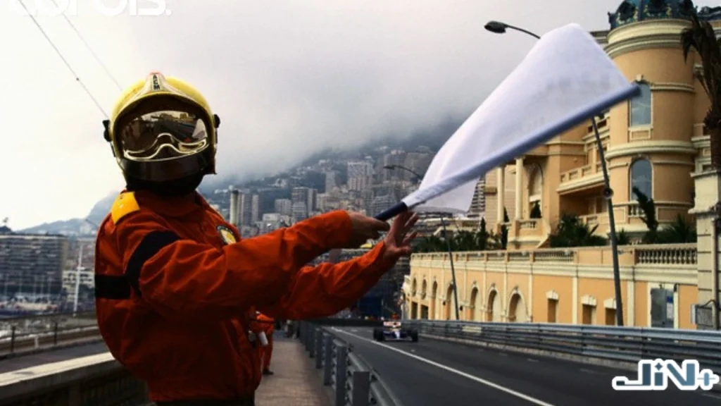 F1白旗慢車提示實景，Marshal在賽道高處護欄旁揮舞白色旗幟，提醒前方有慢速行駛車輛。