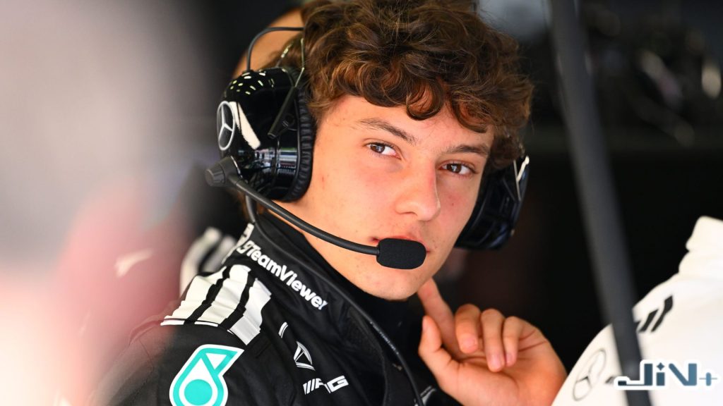 F1Kimi安東內利身穿黑色賓士車隊制服、戴著無線通訊耳機，在維修區維修站凝視賽道的特寫。